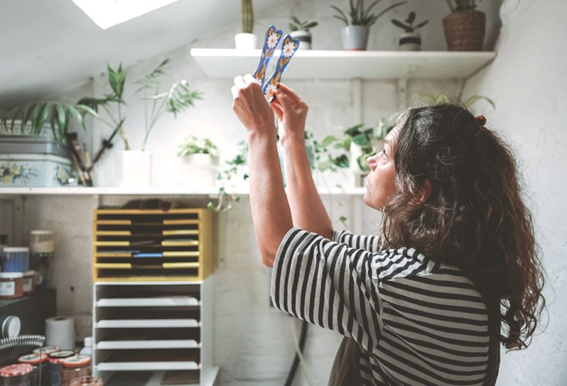 An image of Flora Jamieson in her studio designing her stained glass artwork, this image is used to promote her stained glass workshop at Haymarket Hotel.