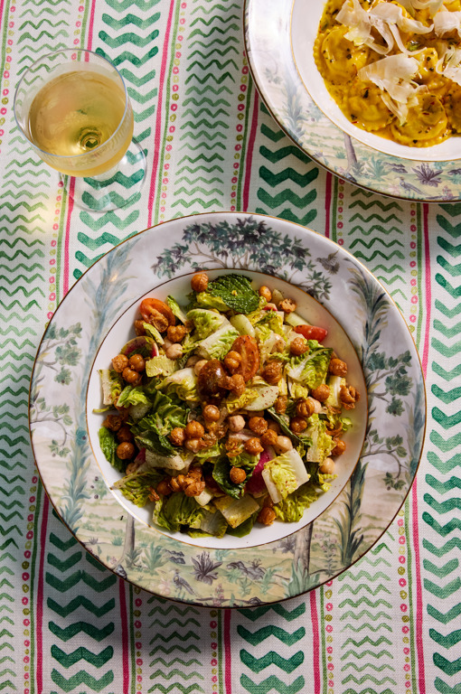 A plate of salad and part of a bowl of ravioli on a table with a glass of wine at Warren Street Bar