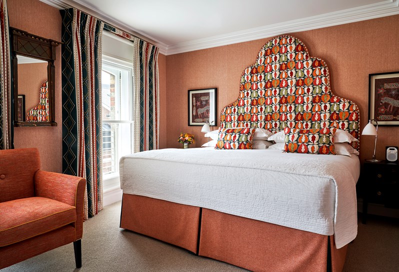 A red themed room at Charlotte Street Hotel with an orange, red and green leaf patterned headboard with matching cushions