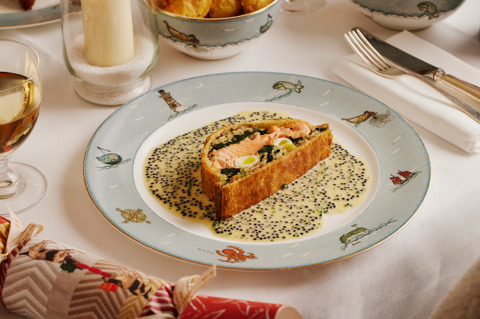 This image shows a close up image of the Salmon coulibiac, Exmoor caviar butter sauce on Sailors Fairwell crockery with roast potatoes in the background. This is to promote the Christmas Day Menu at Ham Yard Hotel.