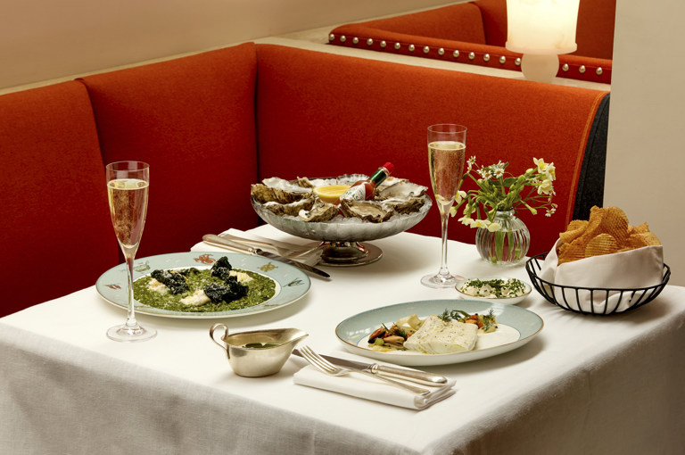 Wide shot of oysters, poached brill, chard risotto and game chips in the restaurant at Ham Yard Hotel 