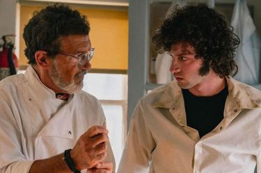 A still from 'Tony'. An older man in chef whites looks in to the eyes of a young man dressed in a shirt standing next to him