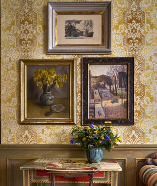 A series of paintings from Bloomsbury Group articles hang against patterned wallpaper at Charlotte Street Hotel in London