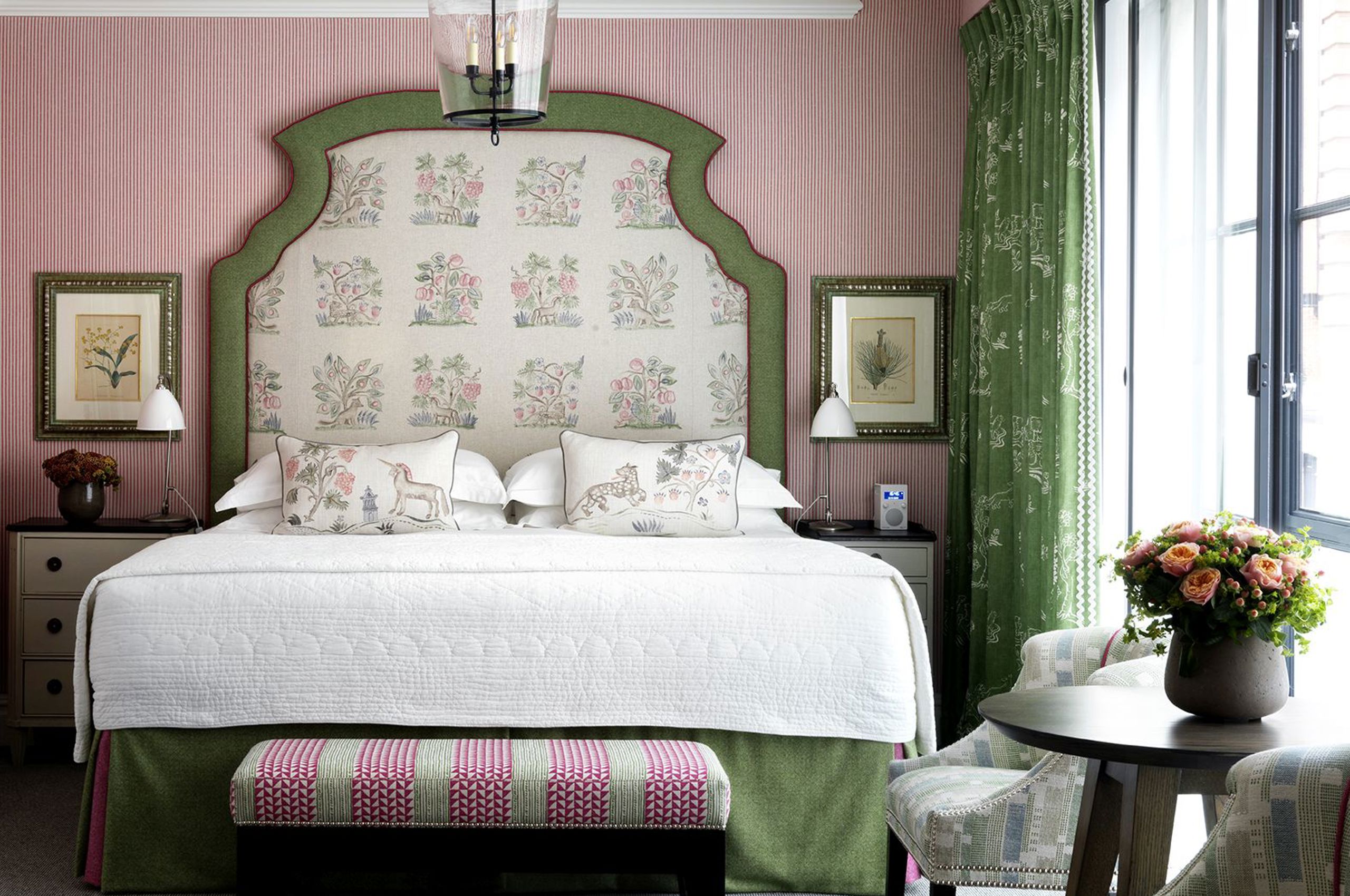 Ornate upholstered headboard bed with floral pillows and green curtains
