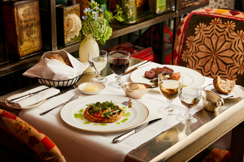 A wide shot of main courses on a table at Refuel. Plates of vegetable tart and beef with a side of bread