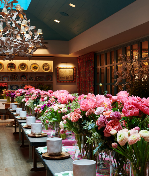 Shot of multiple arrangements of bright pink flowers positioned across a long table.