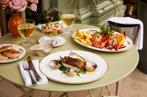 A wide close-up shot of an outdoor dining set up at Oscar Bar and Restaurant: there are seafood dishes and white wine.