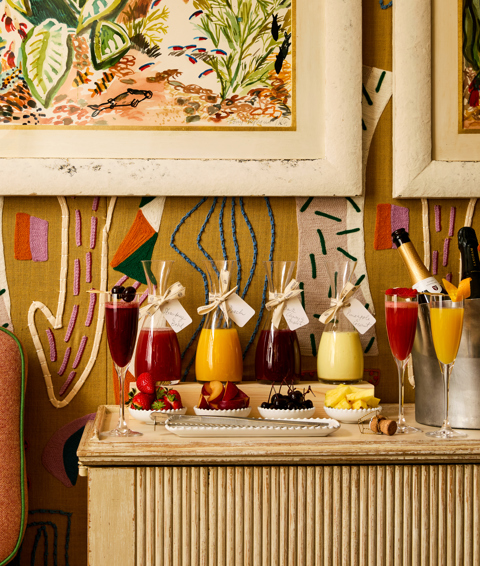 A portrait shot of the Bellini bar in the Dora Carrington Room at Charlotte Street Hotel: there are various types of Bellinis being served in jugs, along with fruit garnishes