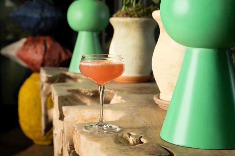 A close-up wide angle shot of a fruity cocktail served in a coupe glass at The Crosby Bar