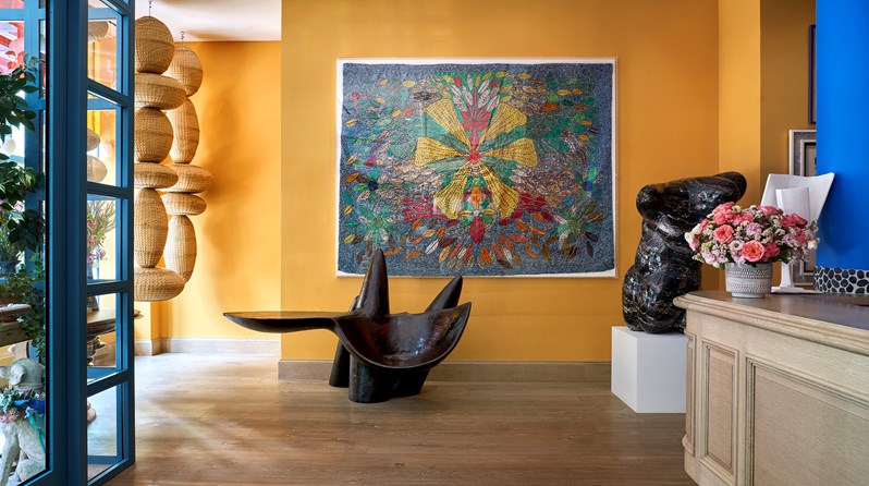 The lobby at Warren Street Hotel with a check-in desk on the right-hand side and a series of sculptures including a set of woven totems hung from the ceiling