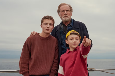 A still from the film '500 Miles': the image portrays a grandfather with his two grandsons standing together on a ship out at sea