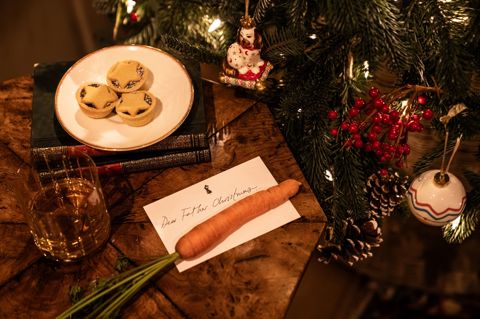 This image shows a Christmas scene at Haymarket Hotel, featuring mince pies and a glass of whisky beside a decorated Christmas tree, with a handwritten letter to Father Christmas and a carrot left out for his reindeer.