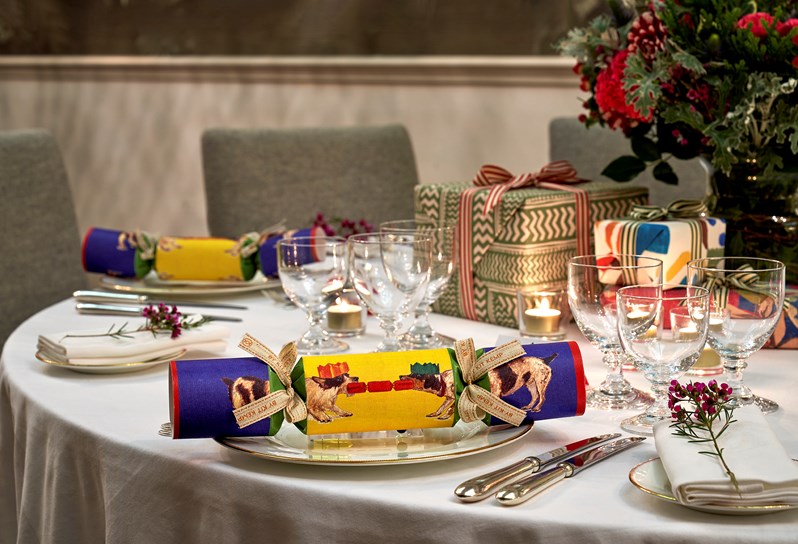 A closeup of Christmas crackers, bouquet of flowers and presents on a round table dining setup in the Shooting Gallery.
