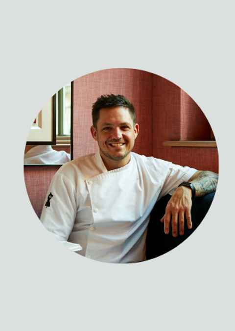 A circle crop of a headshot of Head Chef Richard Wilkins sat in his chef whites