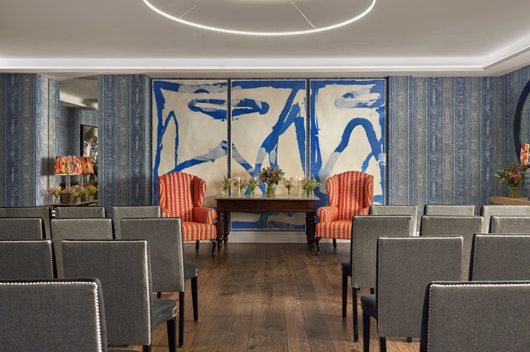 An image of the wedding set in The Indigo Room, a private event room, in The Soho Hotel. With 4 rows of 8 grey chairs across the room, with an aisle down the middle.