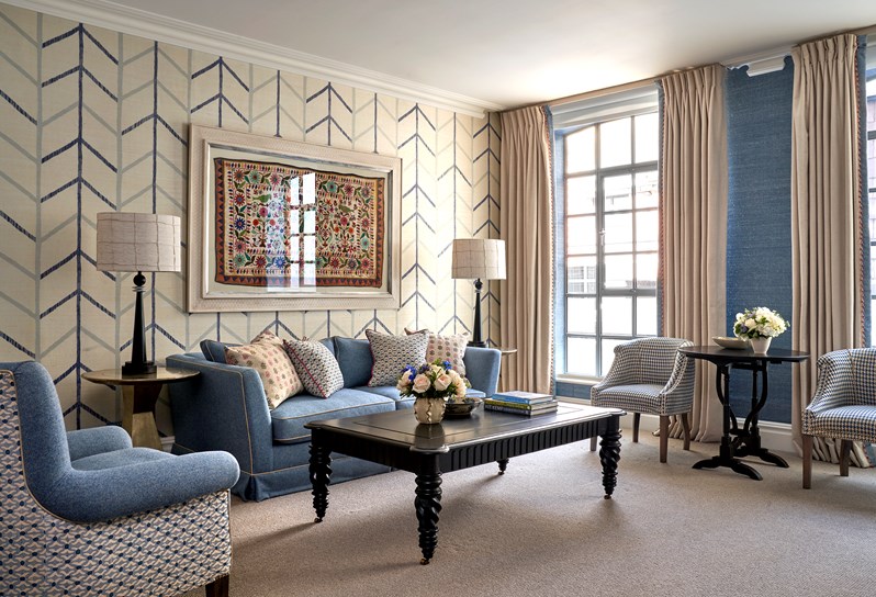 The seating area in the living room of a connecting Junior Suite, Room 109 that has a sofa, an arm chair as well as two table chairs.