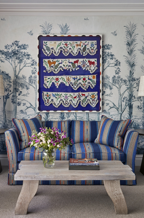 The sitting area of the bedroom in a Deluxe Junior Snug Suite at Ham Yard Hotel, featuring a blue sofa, armchair and coffee table with two small side tables and lamps either side