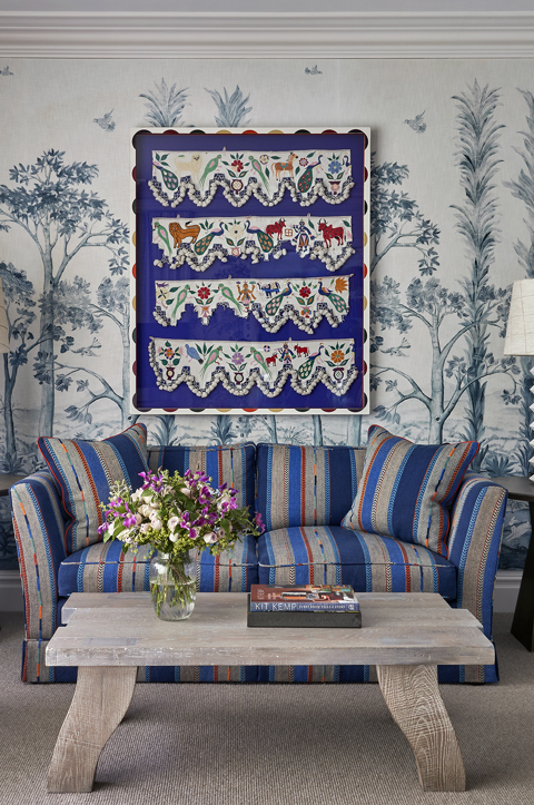 The sitting area of the bedroom in a Deluxe Junior Snug Suite at Ham Yard Hotel, featuring a blue sofa, armchair and coffee table with two small side tables and lamps either side