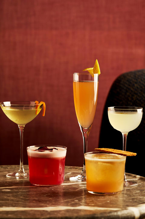 A table of brightly coloured cocktails in different glass styles on a table at Brumus