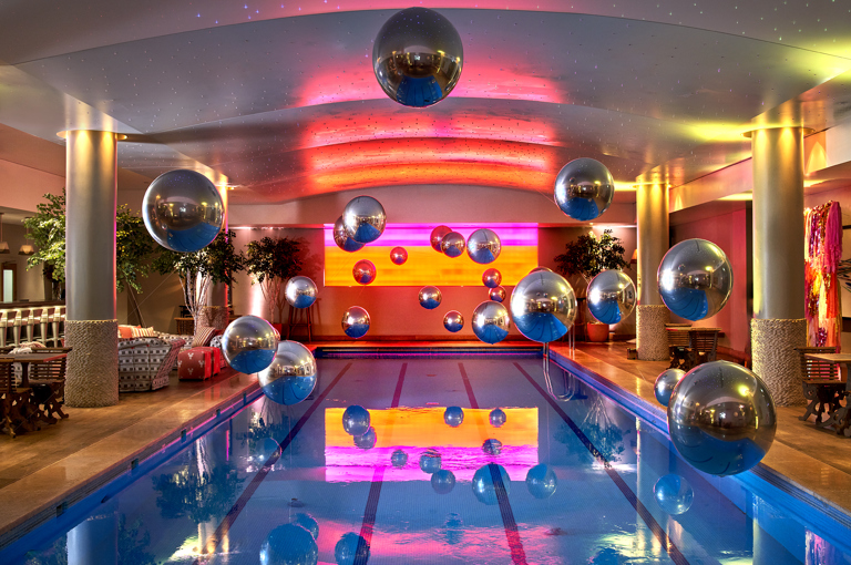 The pool at Haymarket Hotel decorated for a party with silver helium baloons floating over the water