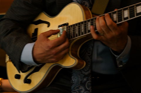 A landscape image of a band playing jazz music, the image focuses on the man playing the the guitar in the Warren Street Bar & Restaurant at Warren Street Hotel.