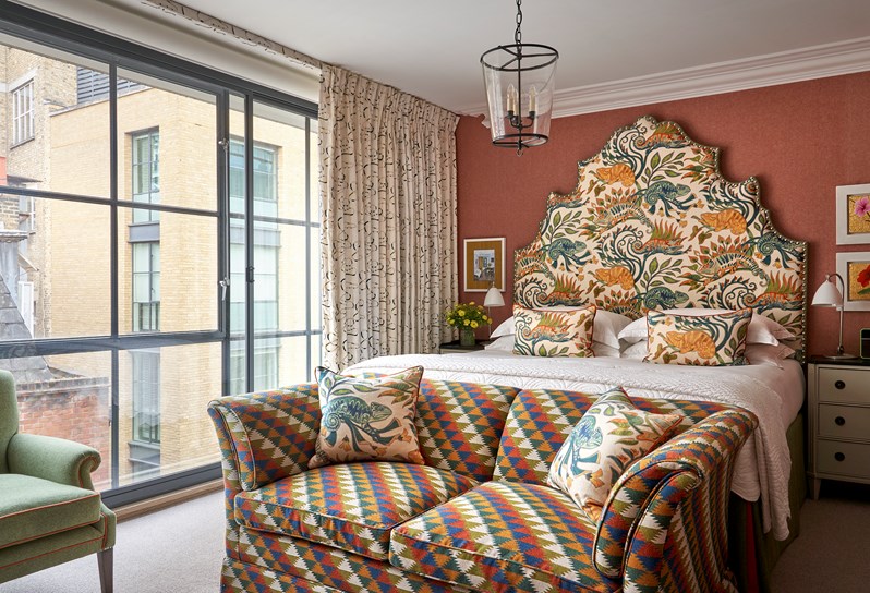 A room at Ham Yard Hotel with a large statement headboard and a sofa at the end of the bed