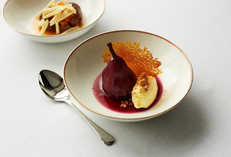 Dessert dish with mulled wine poached pear, toasted hazelnuts and vanilla ice cream