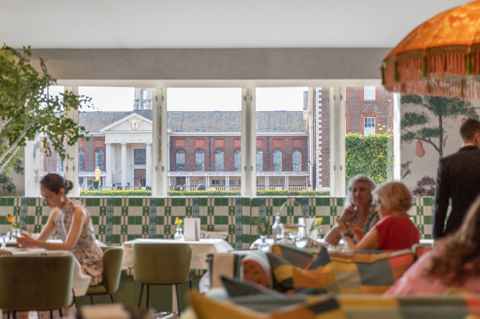 A shot looking across Refuel Cafe at Treasure House Fair, with a view of Royal Hospital Chelsea. Customers can be seen out of focus sitting on tables in the cafe