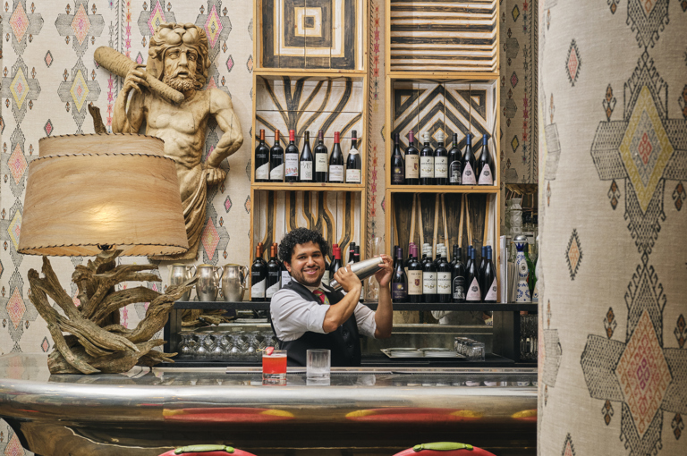 A bartender shaking a cocktail behind the bar at The Whitby Hotel