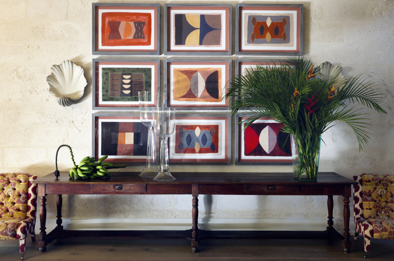 Wide Shot of the Hallway at Rossferry with bunch of banana, a vase of palmtree, and two big glasses ontop a wooden console and some art work.