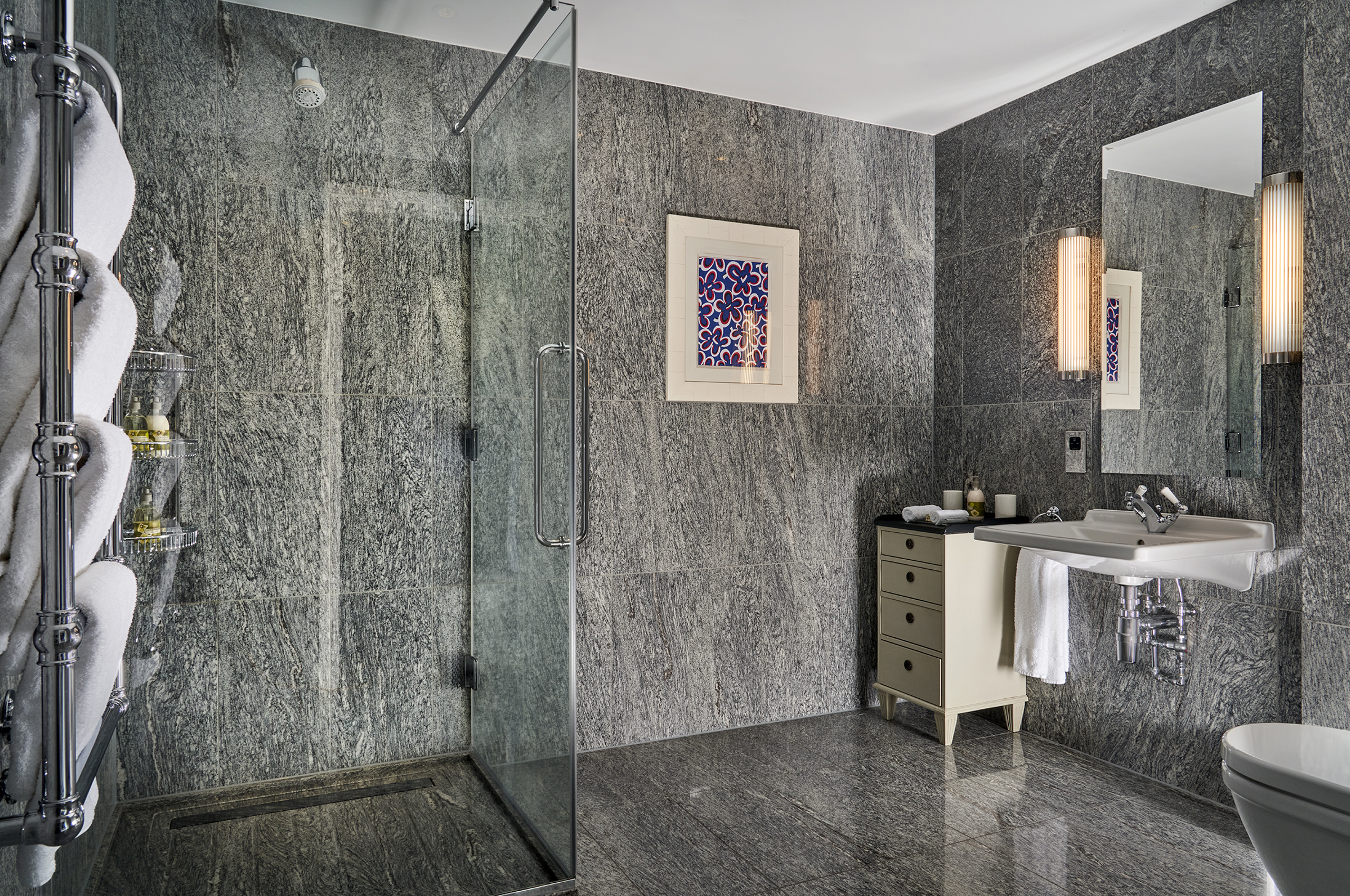Luxury bathroom with marble walls, glass shower, and sink