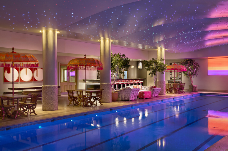 A diagonal shot of the swimming pool and bar at Haymarket Hotel looking across to the pool bar area