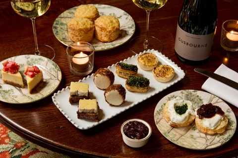 A close up shot of the items in Afternoon Cheese at Brasserie Max at Covent Garden Hotel. There are plates of small cheese-inspired pastries, scones and a miniature cheesecake on a table 