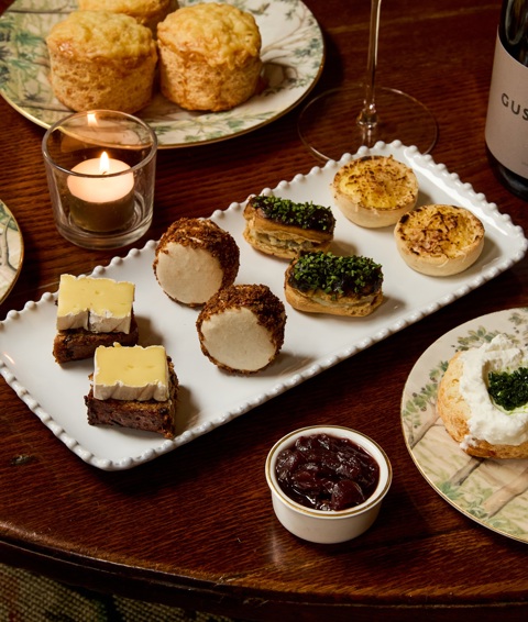 A close up shot of the items in Afternoon Cheese at Brasserie Max at Covent Garden Hotel. There are plates of small cheese-inspired pastries, scones and a miniature cheesecake on a table