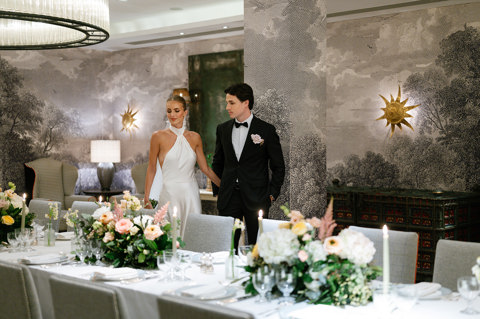 A bride and groom look at their decorated wedding tables in The Windmill Room at Ham Yard Hotel