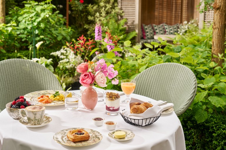 Breakfast in the garden at The Orangery. Table displays a pot of yoghurt and plates of pastries and eggs with smoked salmon shot in the garden