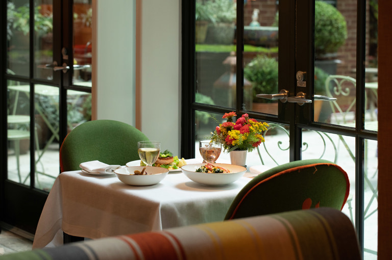 A wide shot of a table at The Crosby Bar. There are dishes of salmon and a lobster salad with two glasses of wine