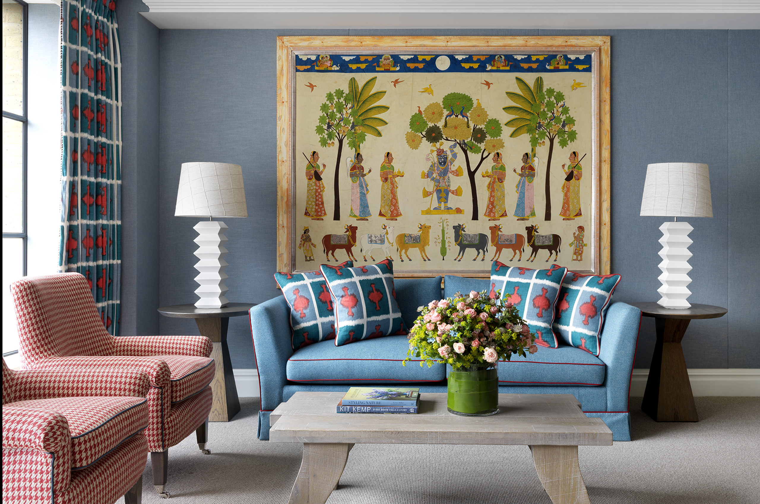 Blue sofa, armchairs, and large framed artwork in a lounge area
