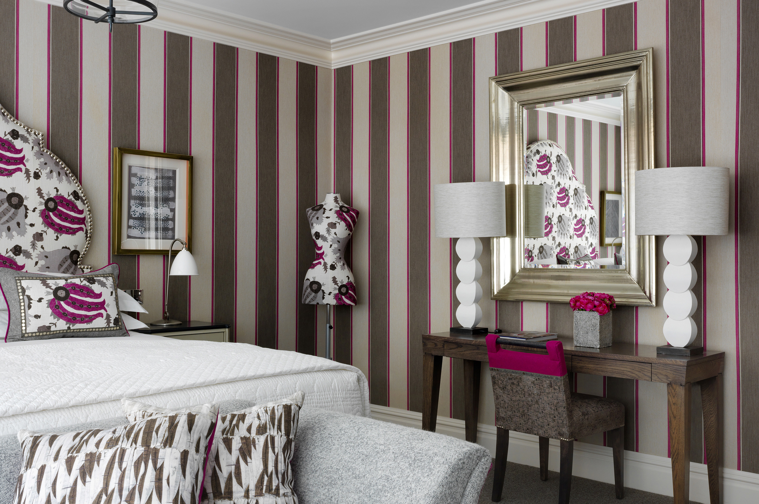 Elegant bedroom with striped wallpaper, floral accents, vanity mirror