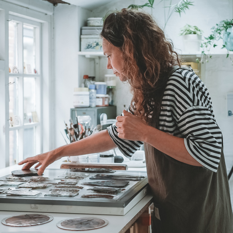 Flora Jamieson working with different stained glass pieces in her studio