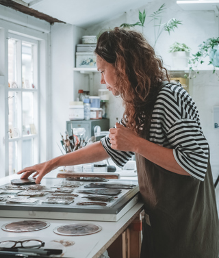 Flora Jamieson working with different stained glass pieces in her studio