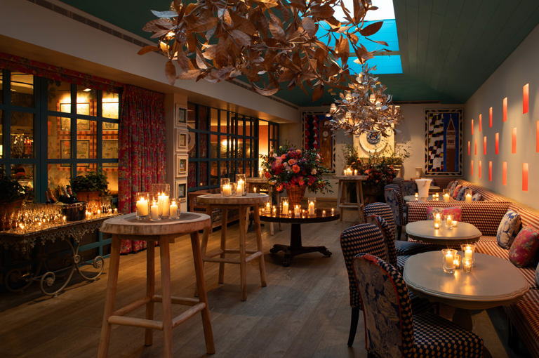Close shot of a warm candlelight, floral decor, and gold leaf chandeliers at Orangery private events room at Warren Street Hotel