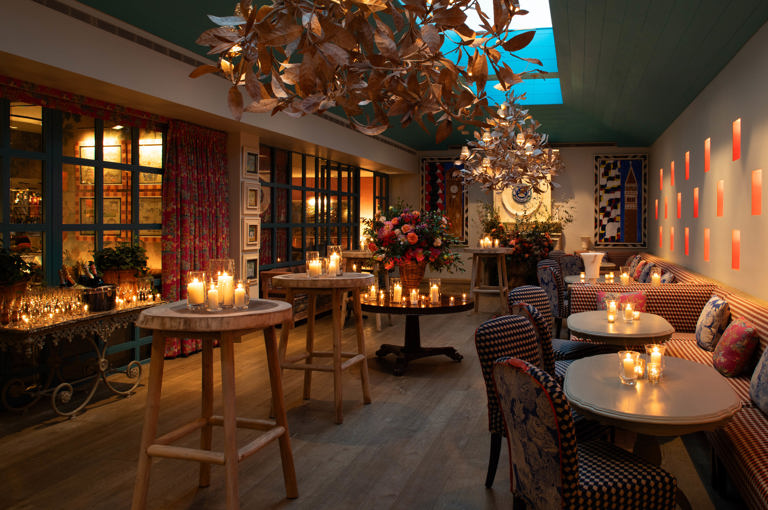 Close shot of a warm candlelight, floral decor, and gold leaf chandeliers at Orangery private events room at Warren Street Hotel