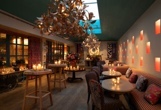 Close shot of a warm candlelight, floral decor, and gold leaf chandeliers at Orangery private events room at Warren Street Hotel