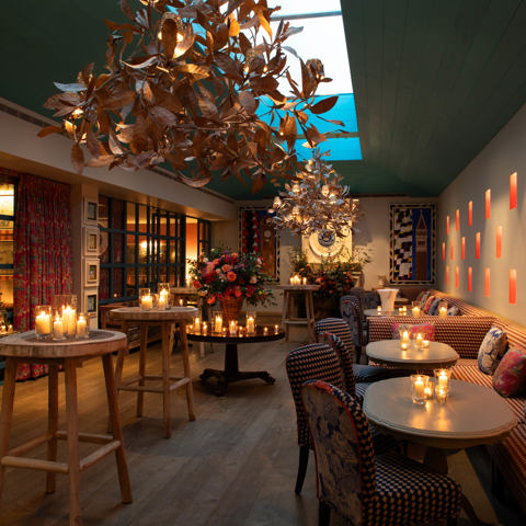 Close shot of a warm candlelight, floral decor, and gold leaf chandeliers at Orangery private events room at Warren Street Hotel
