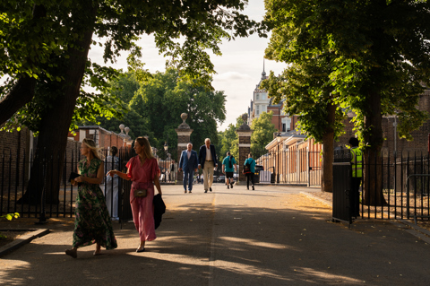 A shot looking through the gates of Royal Hospital Chelsea, where Treasure House Fair takes place. It is a sunny day and people can be seen walking through in smart clothing in groups