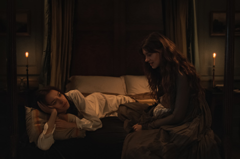 A still from the film 'Sense and Sensibility'. Two women sit on a four poster bed in a dimly lit room