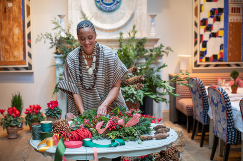 Florist Tawana Schlegel creating a Christmas wreath with foliage and berries on a table at Warren Street Hotel