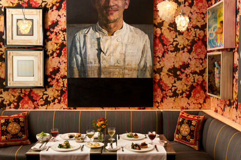 A image of a table at Refuel at Soho Hotel with white linen clothes is set up with multiple dishes from the Summer A La Carte with glasses of red and white wine on each place setting. 