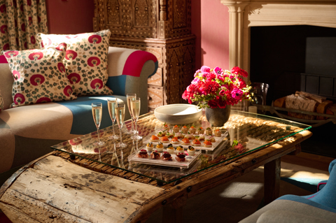 A coffee table in the Drawing Room at Crosby Street Hotel adorned with canapes and flutes of Champagne